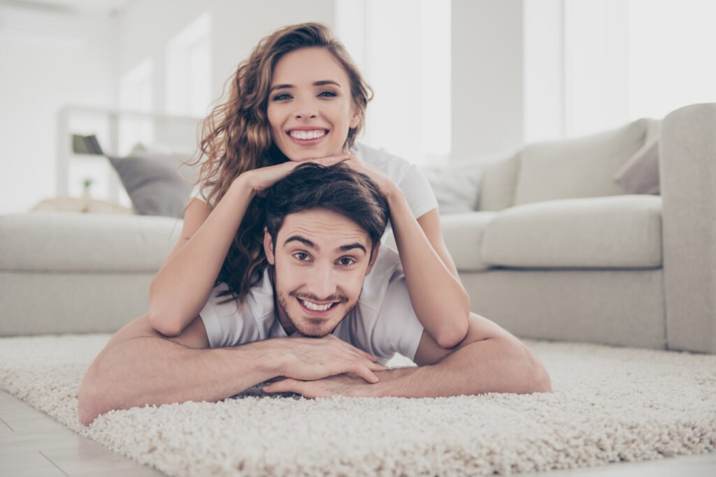 Happy couple lying on the floor together, smiling and relaxed, showing the comfort and emotionally healthy marriage.
