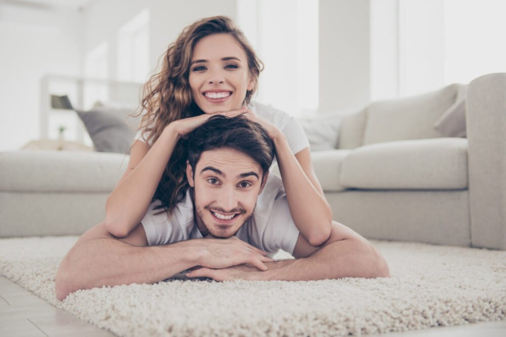Happy couple lying on the floor together, smiling and relaxed, showing the comfort and emotionally healthy marriage.