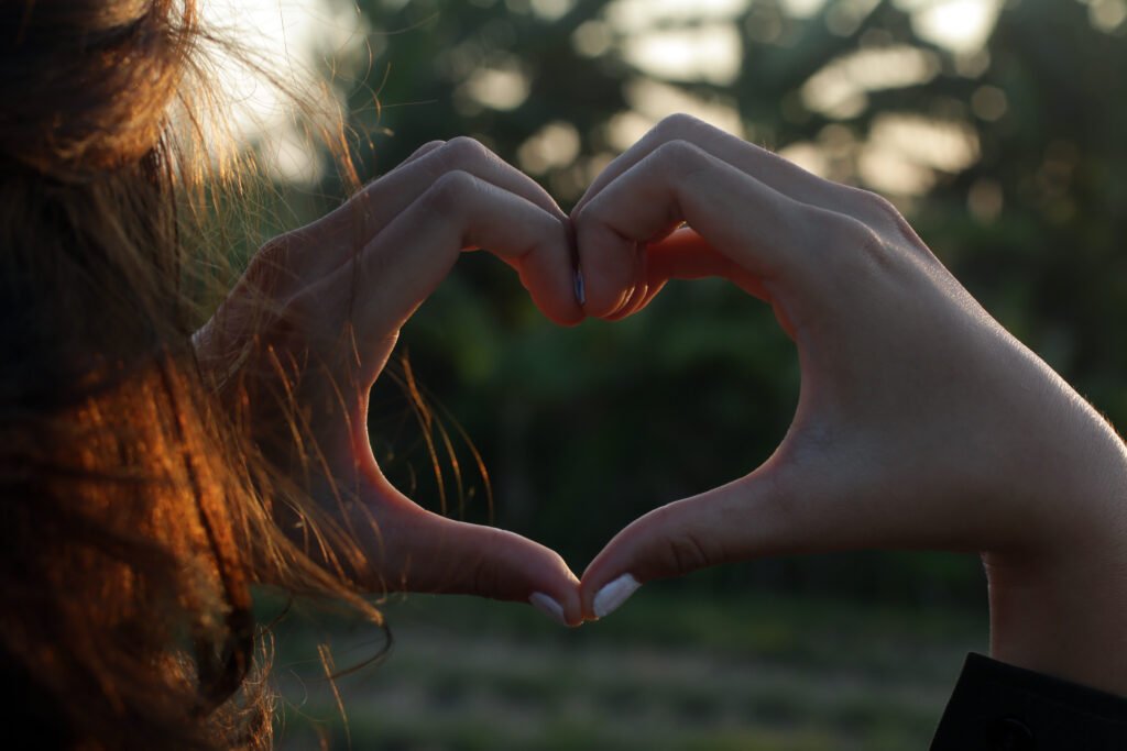 Hands forming a heart shape in soft natural light, symbolizing self love and recovering your self-worth