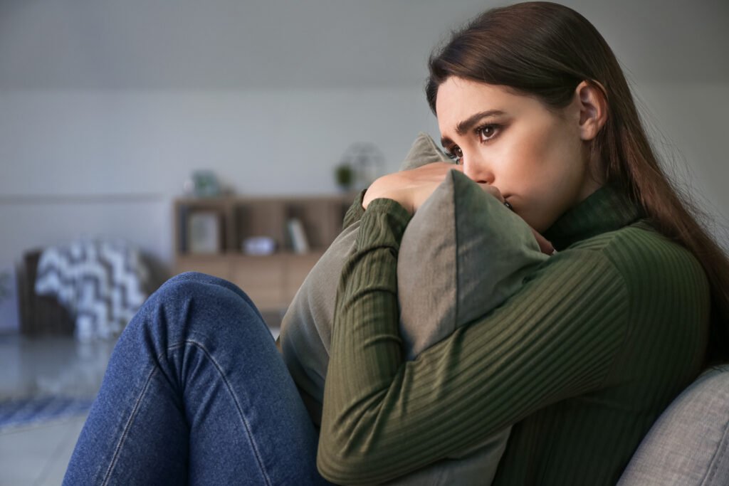Woman sitting alone looking worried while waiting for replies on a dating app