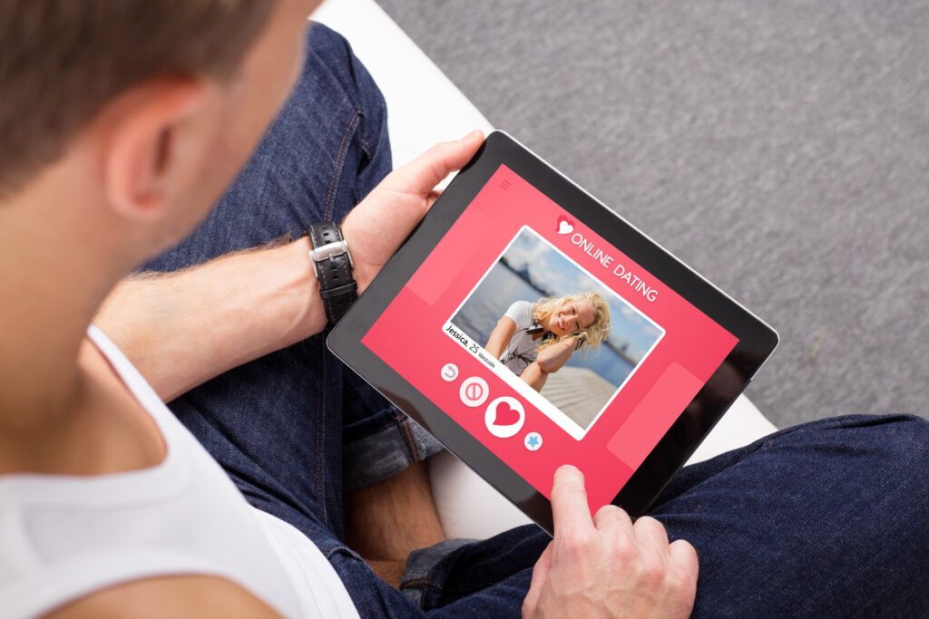 Man using a tablet to view an online dating profile, examining possible red flags that suggest the person may be a catfish.
