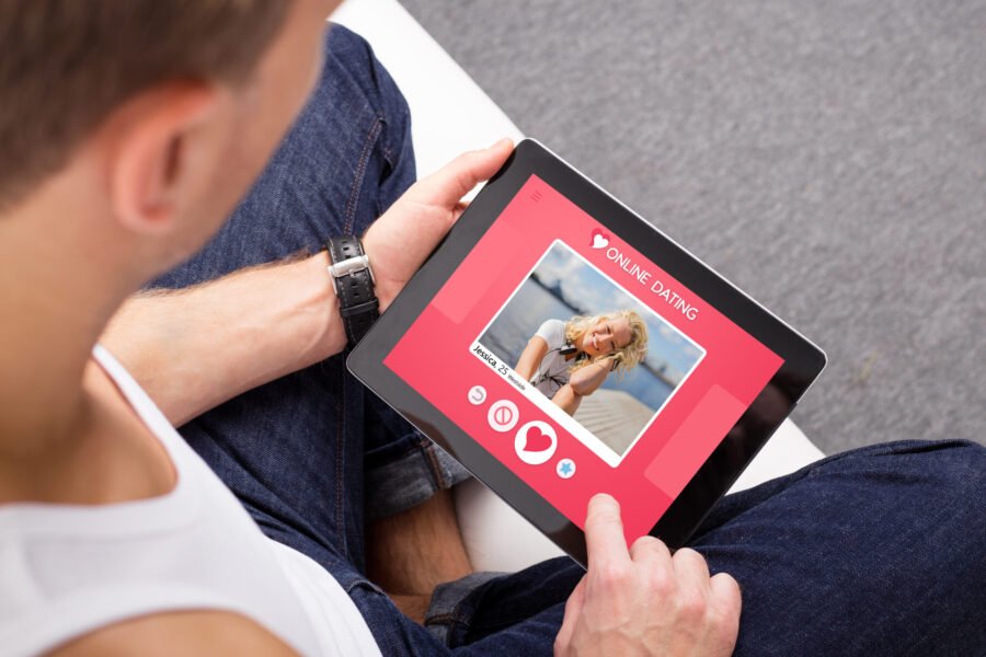 Man using a tablet to view an online dating profile, examining possible red flags that suggest the person may be a catfish.