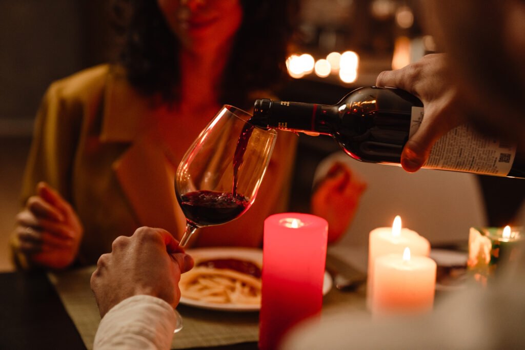 Wine being poured into a glass during a romantic first date dinner with candles.
