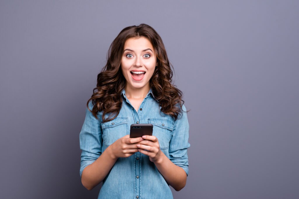 Confident woman smiling while checking her phone, representing how emotional clarity helps get more matches on dating apps.