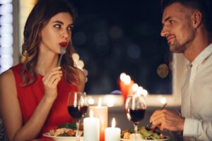 A woman and man sharing eye contact during a romantic first date dinner with candles and wine.