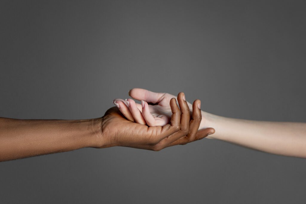 Two hands gently holding each other against a neutral gray background.