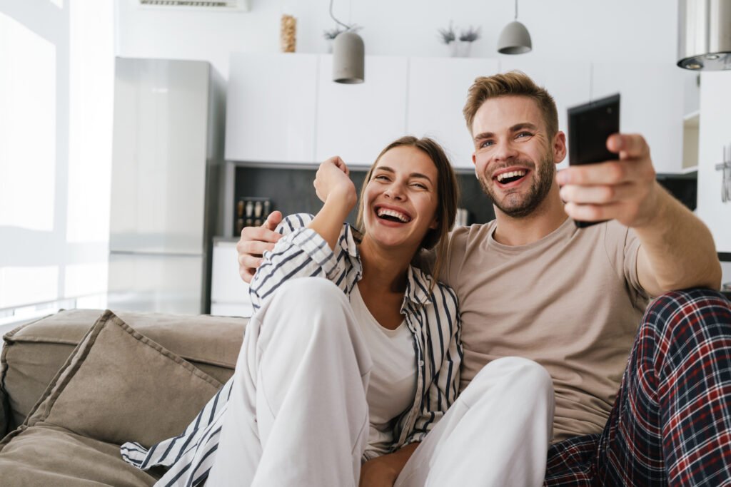 Happy couple sitting together and laughing, showing how partners can feel Emotionally close again after overcoming distance.