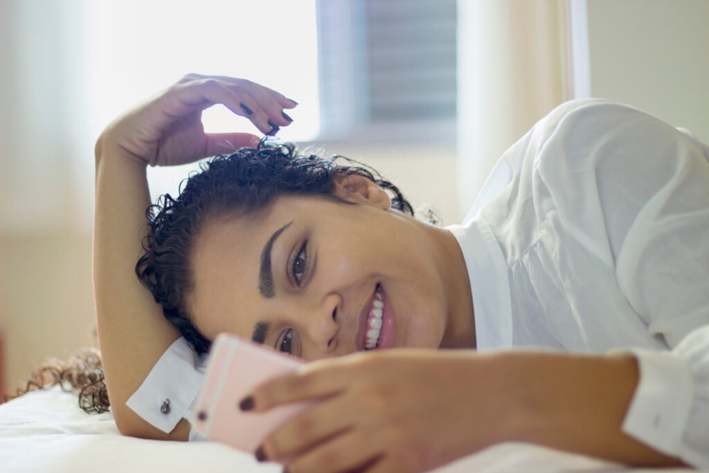 Woman surrounded by multiple Tinder profile cards smiling on couch