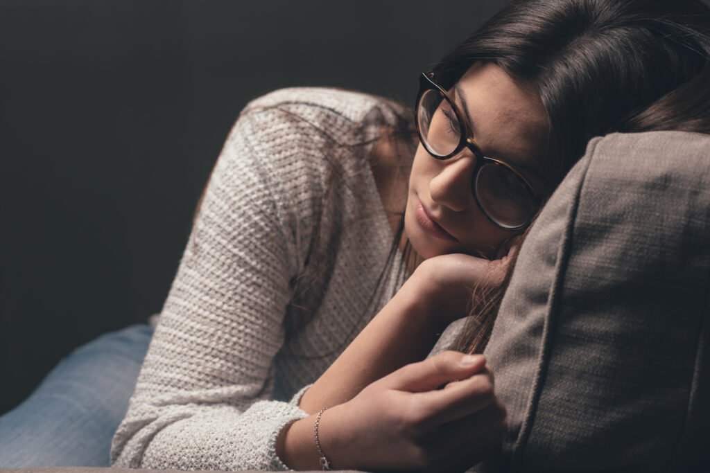 A woman resting quietly on a couch with her eyes closed, representing emotional exhaustion and reflection after being ghosted in dating.