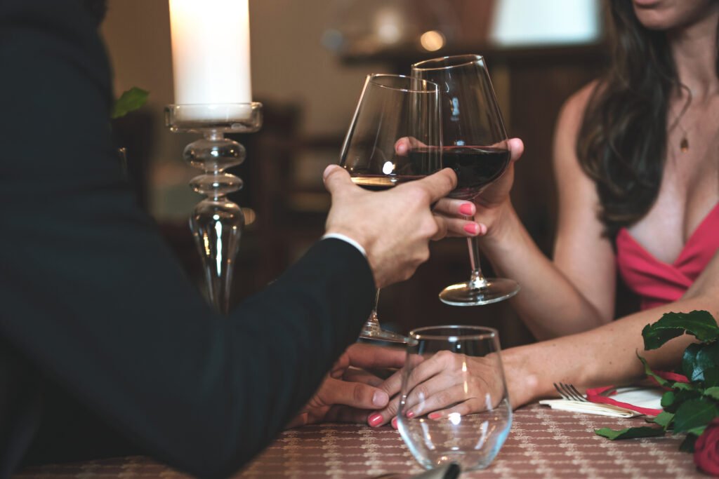 man and woman clinking wine glasses on a first date showing attraction comfort and romantic connection