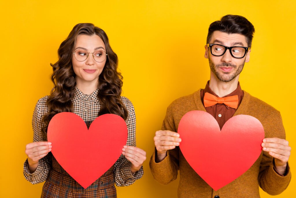 man and woman holding heart shapes and looking at each other representing first date attraction and mutual interest