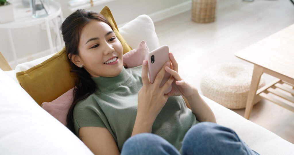 Woman relaxing on couch using dating app on smartphone